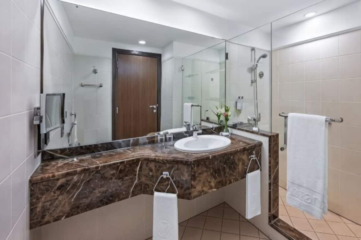 Un baño moderno con tocador de mármol, un espejo grande, un lavabo y una zona de ducha.