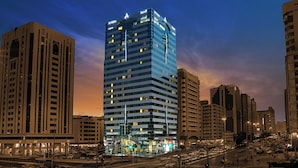 A multi-story hotel with illuminated signage, a prominent entrance, and a busy urban street scene.