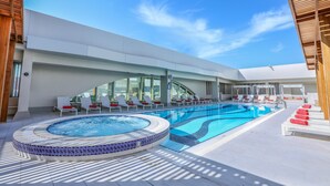 A modern outdoor pool area with lounge chairs and a hot tub.