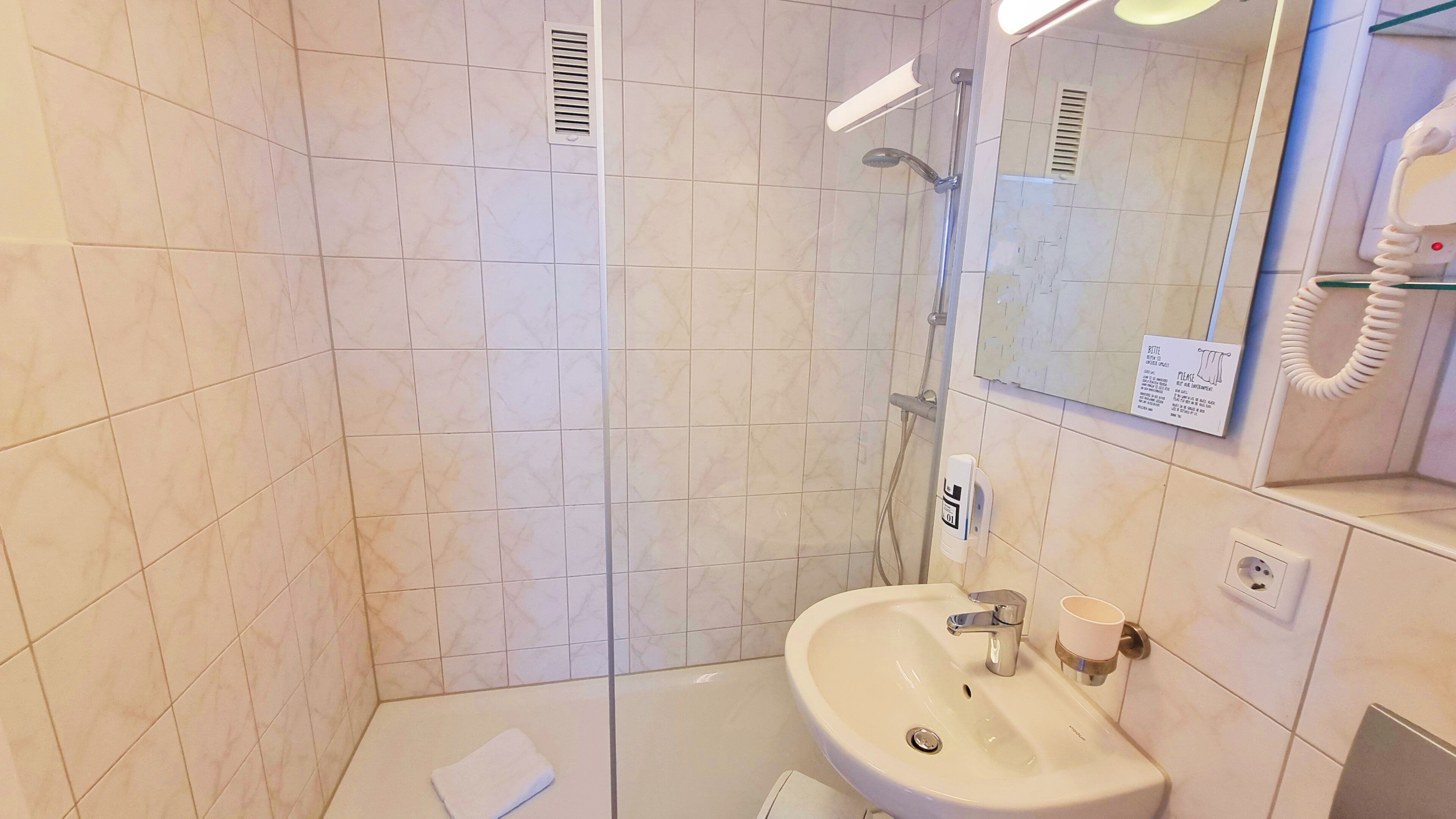 Une salle de bain avec un lavabo, un miroir et une douche.