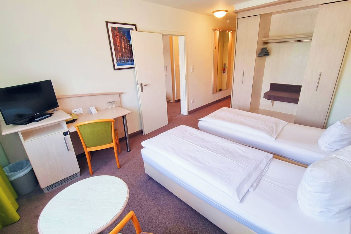 A hotel room with a bed, a desk with a chair, a television, and a small table.