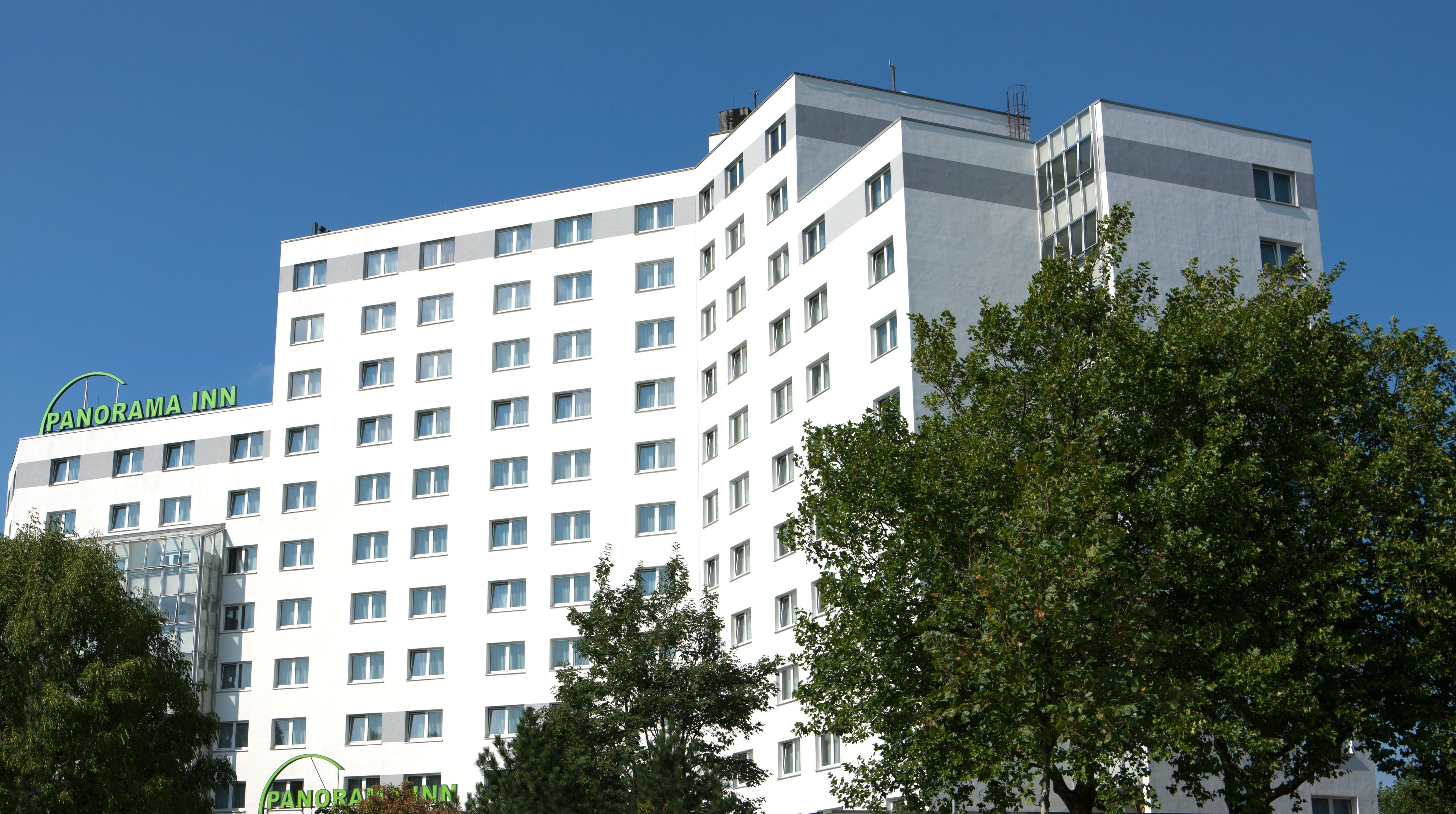 Un hotel de varios pisos con un diseño moderno, con numerosas ventanas y un letrero llamativo que dice "Panorama Inn".