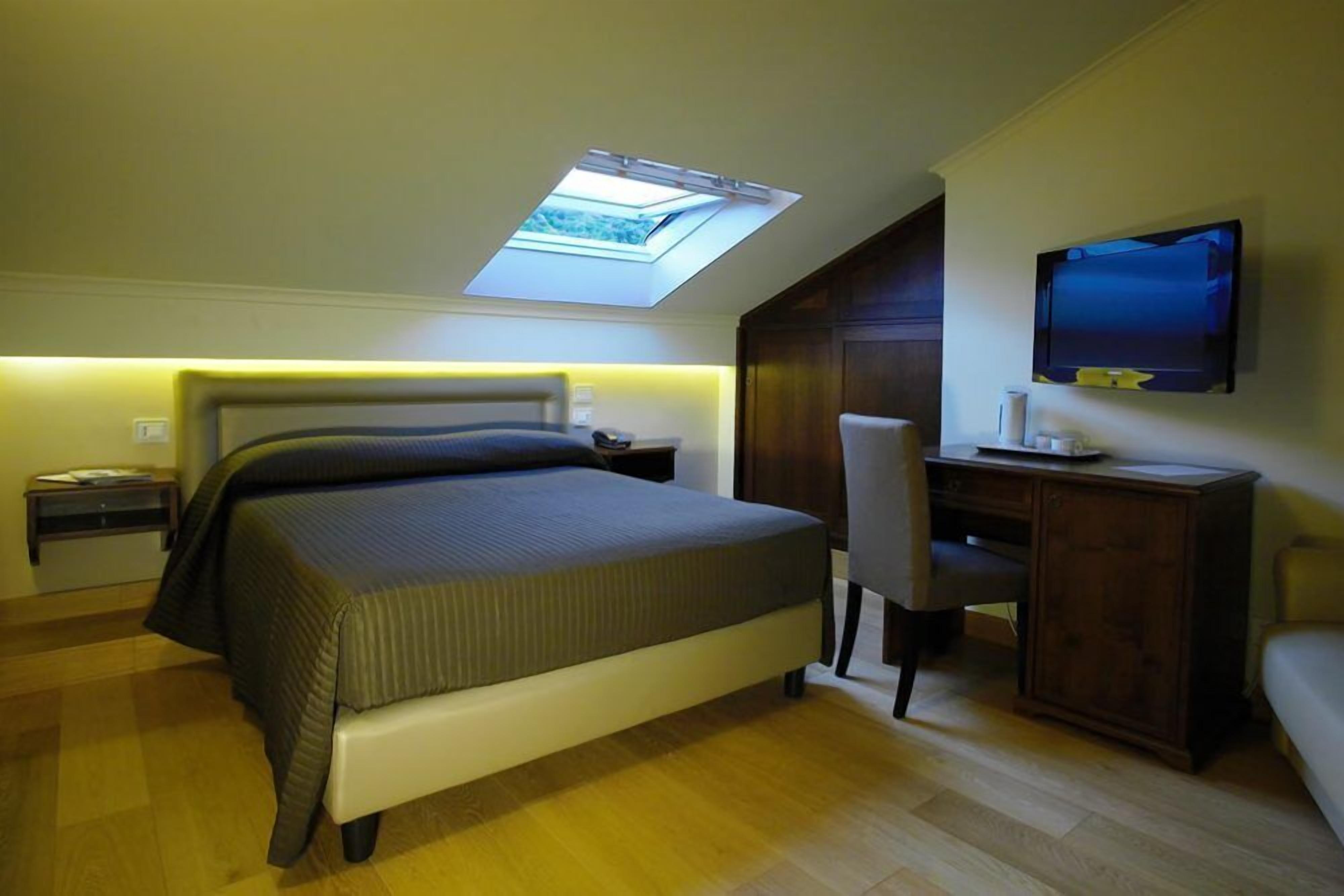 Een slaapkamer met dakraam, een bed, een bureau, een stoel en een televisie.