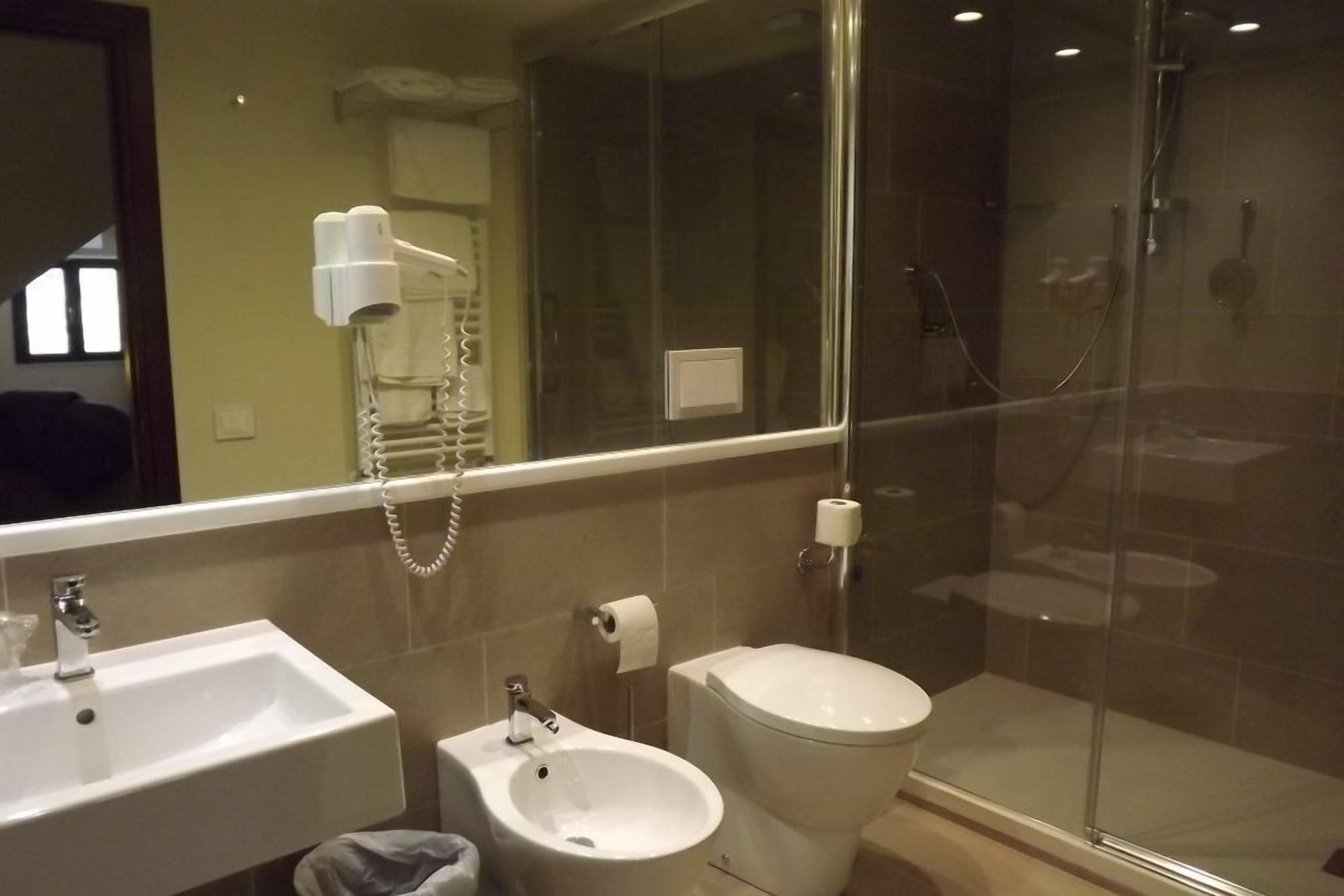 A modern bathroom with a glass-enclosed shower, a bidet, a toilet, and a sink.