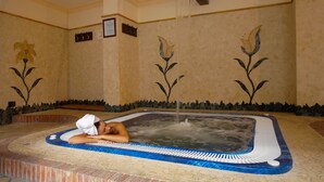 A spa area with a hot tub, a tiled floor, and floral wall designs. - Airone Wellness Hotel (Zafferana Etnea)