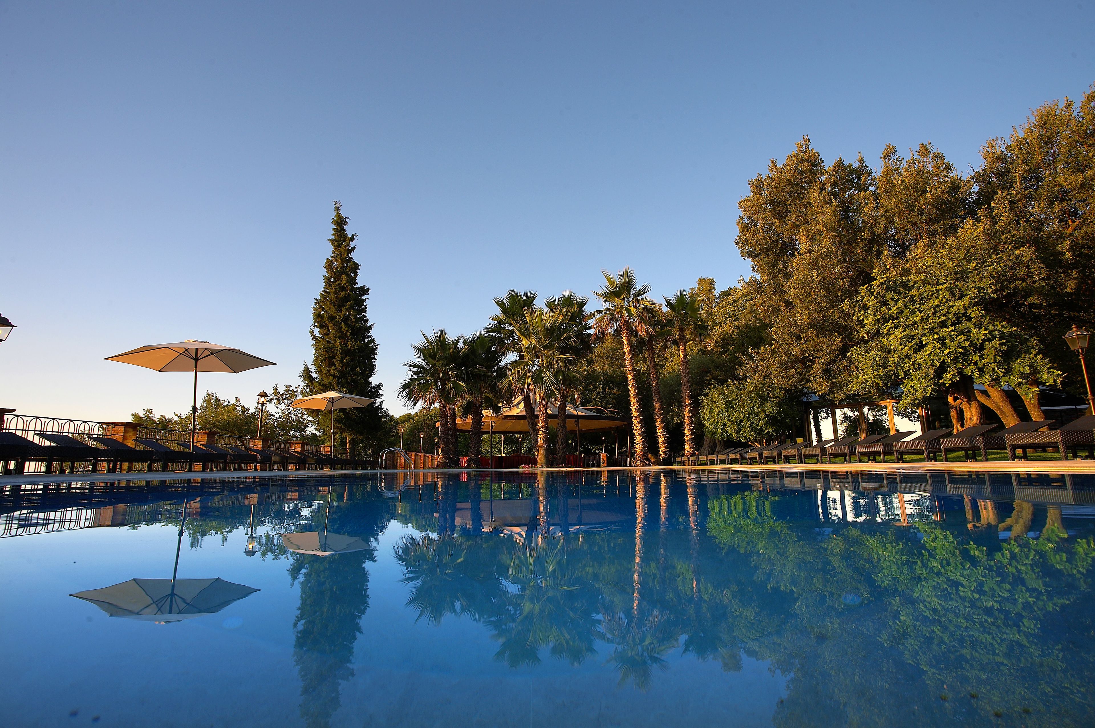 Una piscina techada, una piscina al aire libre, sombrillas