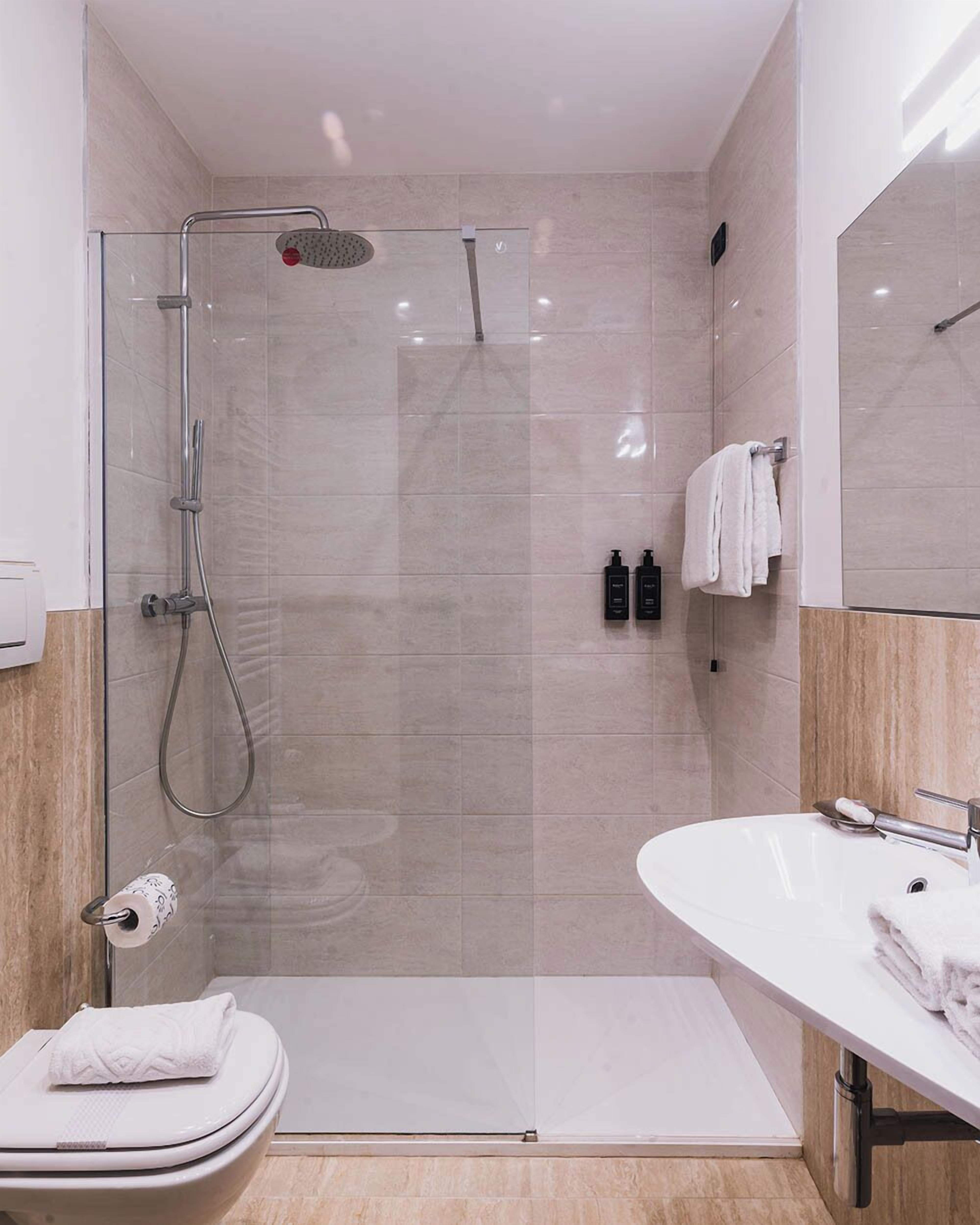 A modern bathroom with a glass-enclosed shower, a white sink, and a toilet.
