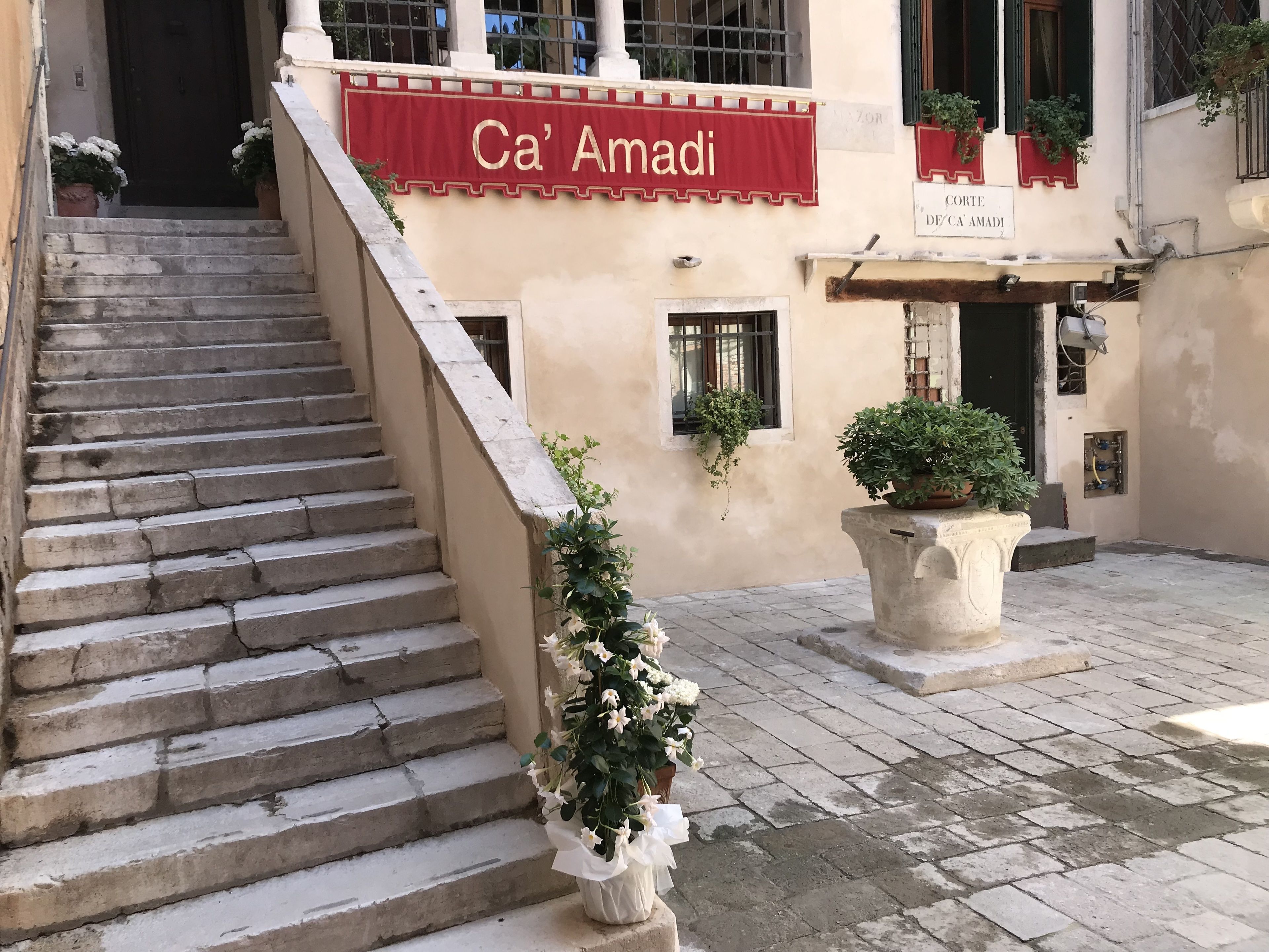 A staircase leading to a building with a red awning labeled "Ca' Amadi."