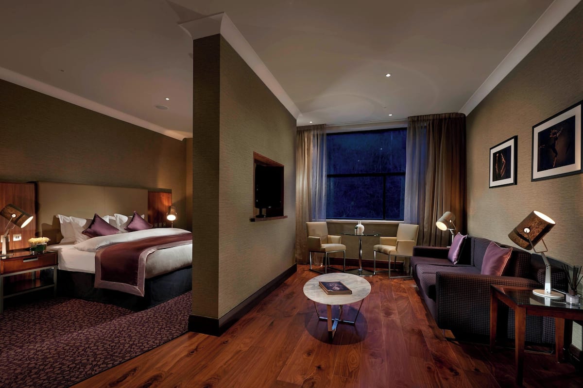 Une chambre d’hôtel avec un lit, un canapé, une petite table et un téléviseur.