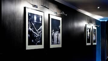 A hallway with framed photographs on the wall, recessed lighting, and a carpeted floor.