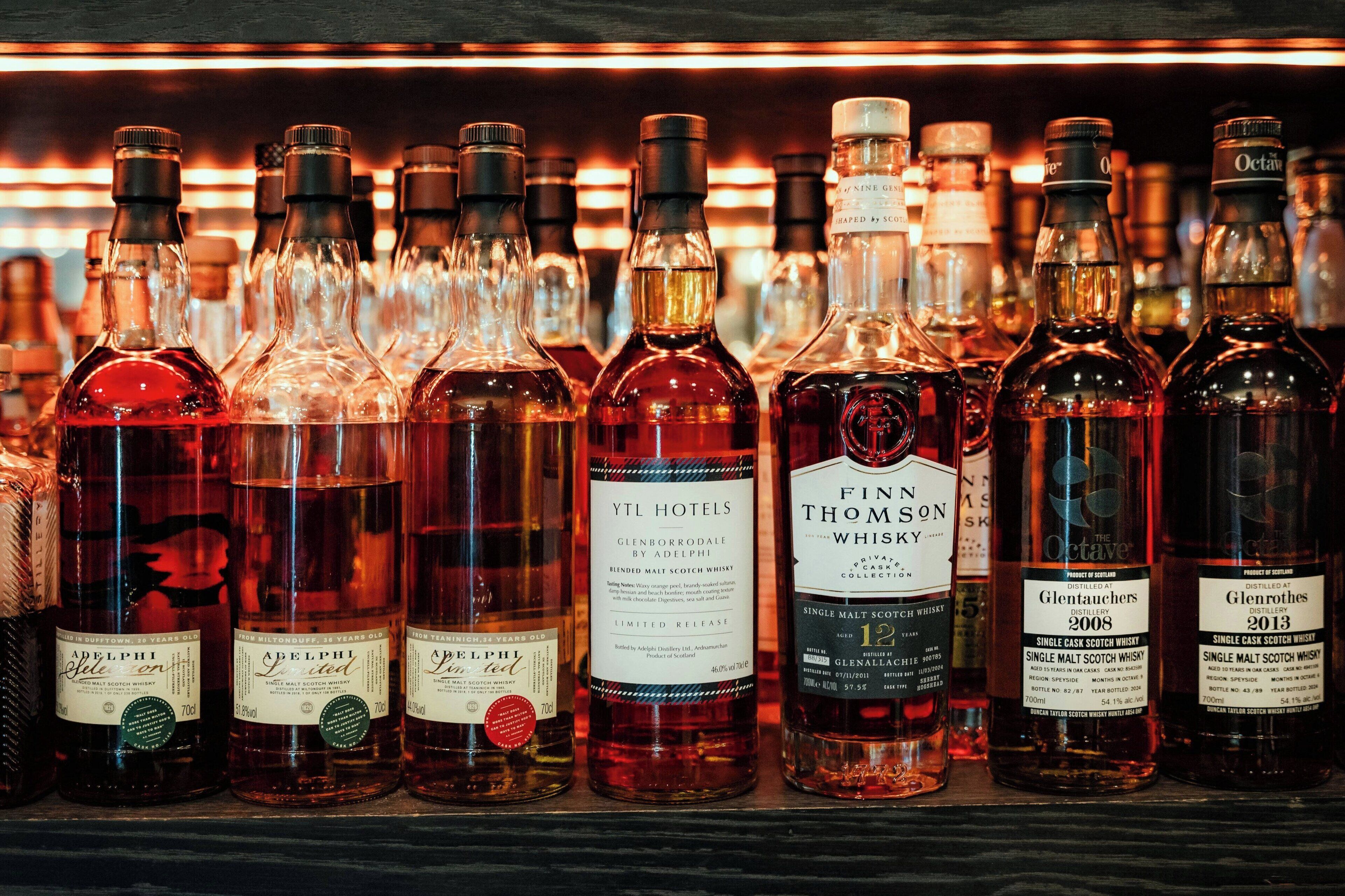 Variedad de botellas de whisky exhibidas en un estante.
