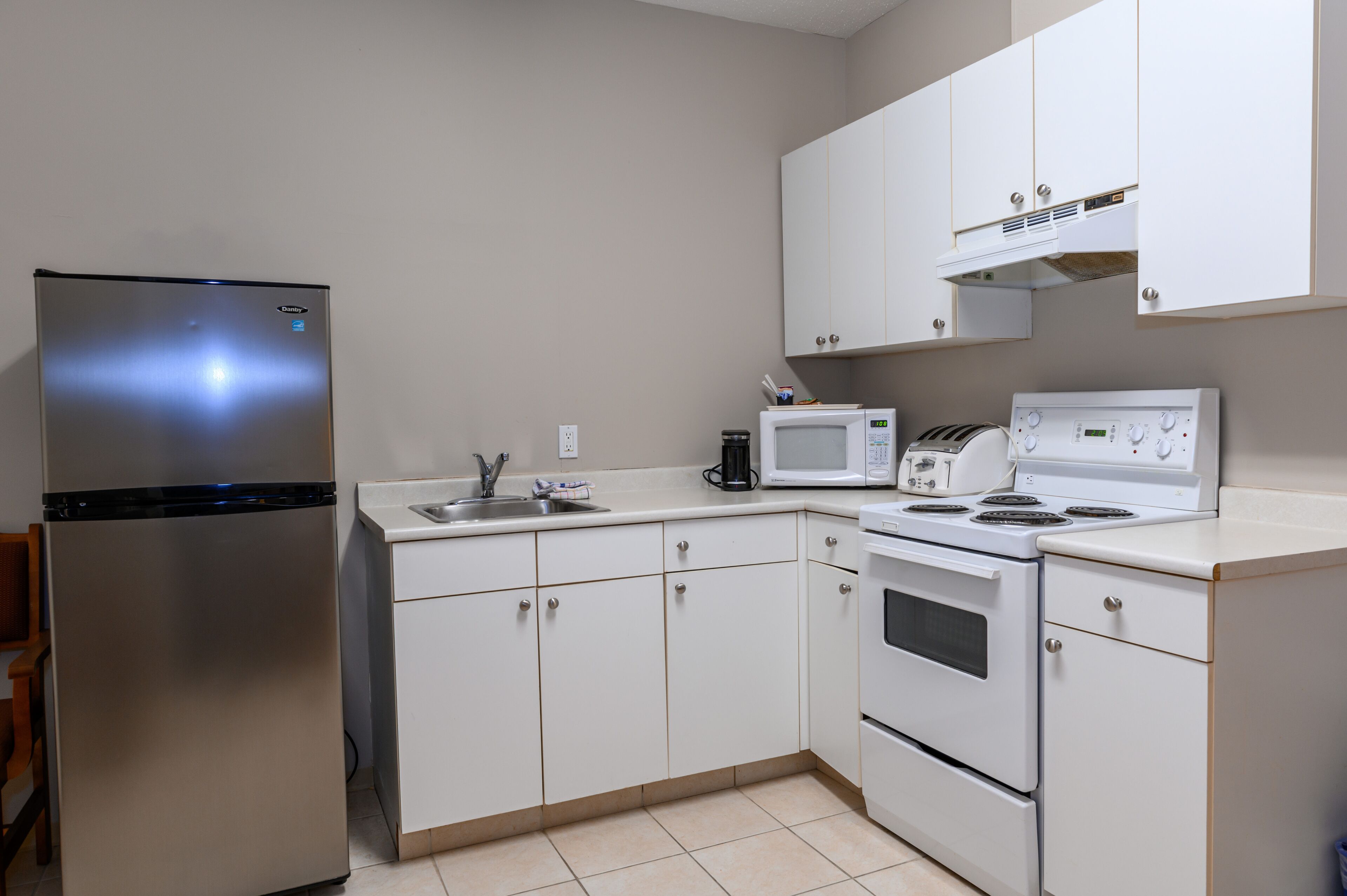 Cocina compacta equipada con refrigerador, microondas, tostadora, pileta y horno.