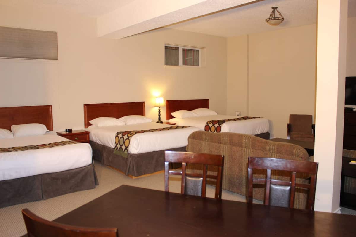 A hotel room with two beds, a small table, and two chairs.