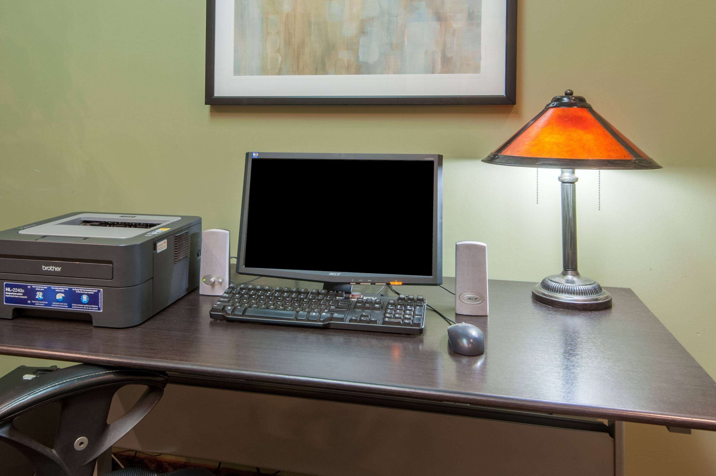 Un bureau avec une imprimante Brother, un écran Acer, un clavier, une souris et une lampe.
