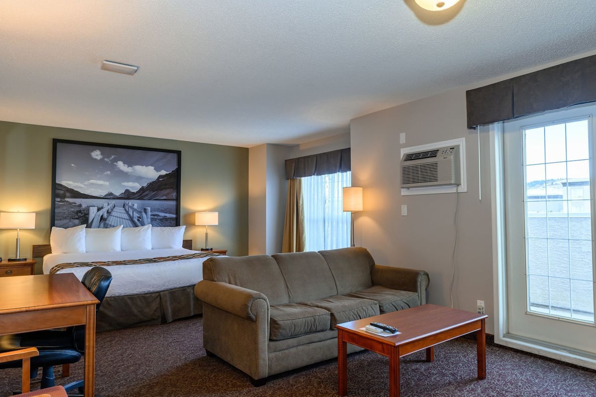 Habitación de hotel con cama, sofá, escritorio y ventana con vistas.