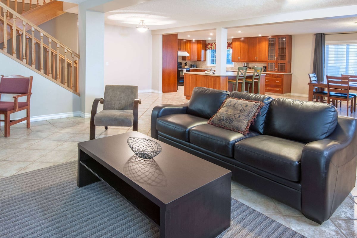 A modern living room with a leather sofa, a coffee table, and a dining area with wooden furniture.