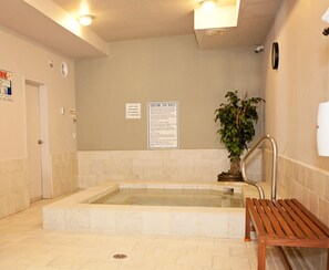 A spa area with a hot tub, a wooden bench, and a potted plant. - Super 8 by Wyndham Cochrane (Cochrane)