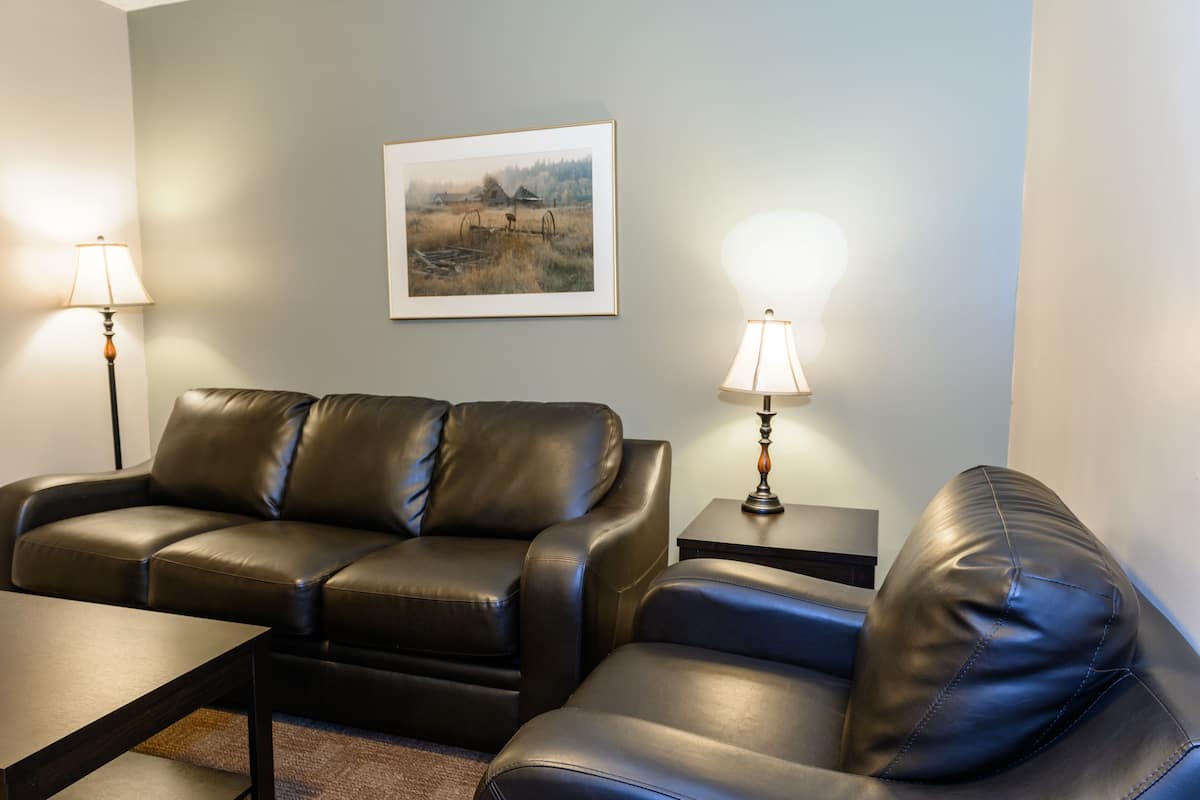 A living room with a sofa set, two side tables with lamps, and a framed picture on the wall.