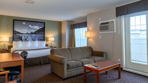 A hotel room with a bed, a sofa, a desk, and a window with a view. - Super 8 by Wyndham Cochrane (Cochrane)