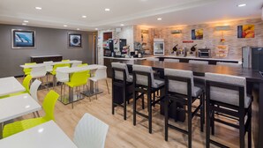 Un comedor moderno con mesas y sillas, una barra de cocina y varios electrodomésticos.