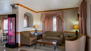 Un hall de hotel con zona de estar, mostrador de recepción y un elemento decorativo en la pared.