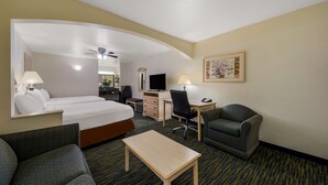 Una habitación de hotel con cama, escritorio, silla y una mesita.