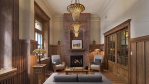 A spacious living room with a fireplace, wooden paneling, and a large chandelier. - Auberge Saint-Pierre (Québec City)