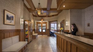 A hotel lobby with wooden paneling, a reception desk, a bench, and a staircase leading to another area. - Auberge Saint-Pierre (Québec City)