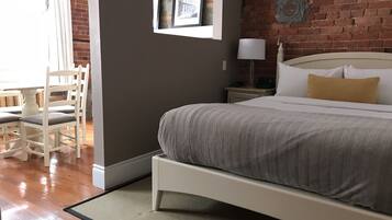Un dormitorio con cama, mesita de noche, lámpara, silla y escritorio.