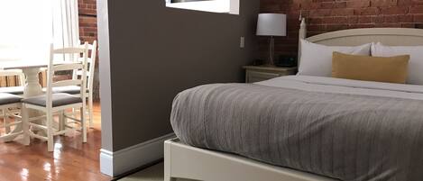 A bedroom with a bed, a nightstand, a lamp, a chair, and a desk.