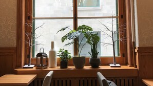 A dining area with a large window, wooden bench seating, and potted plants. - Auberge Saint-Pierre (Québec City)