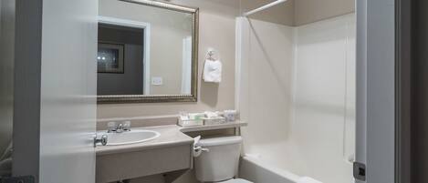A bathroom with a sink, toilet, and shower. There is a mirror with lights above it.