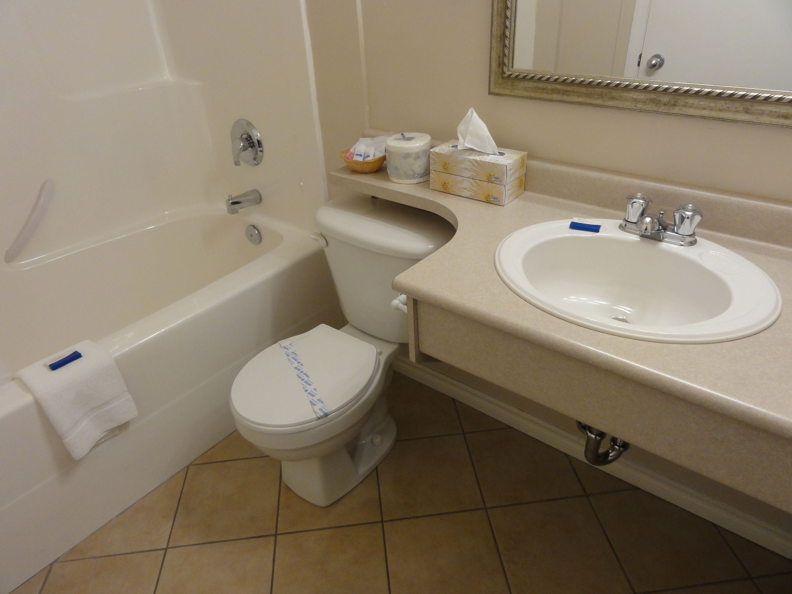 A bathroom with a bathtub, toilet, sink, and a mirror.
