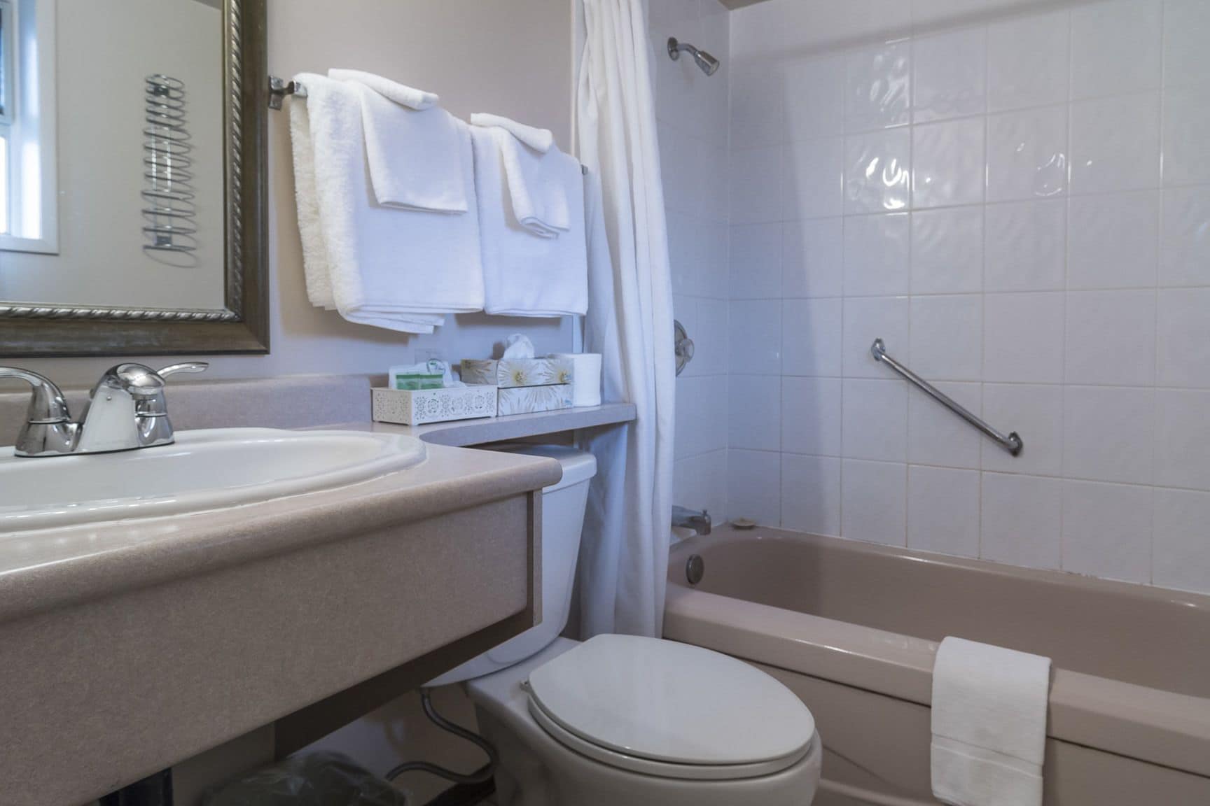 A bathroom with a sink, mirror, and a bathtub.