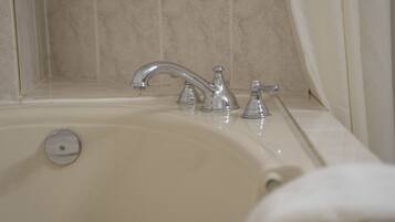 A bathroom with a bathtub, a single faucet, and a showerhead.