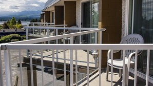 A balcony with white railings, a chair, and a table. - Port Augusta Inn and Suites (Comox)