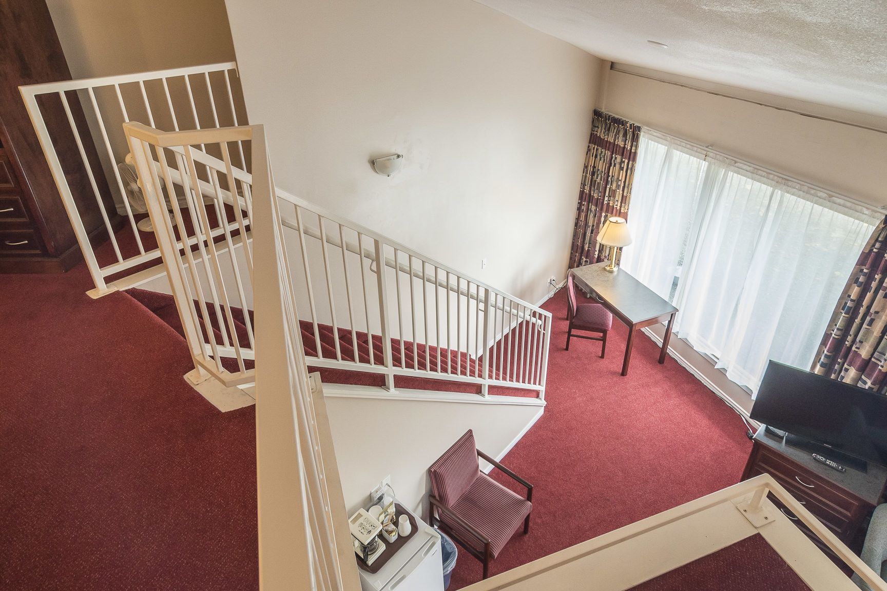 A multi-level room with a staircase, a dining area, and a television.