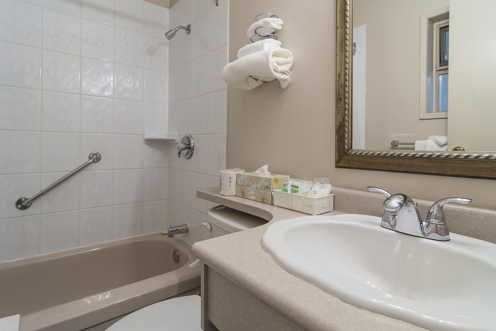 A bathroom with a bathtub, a sink, a mirror, and a towel rack.