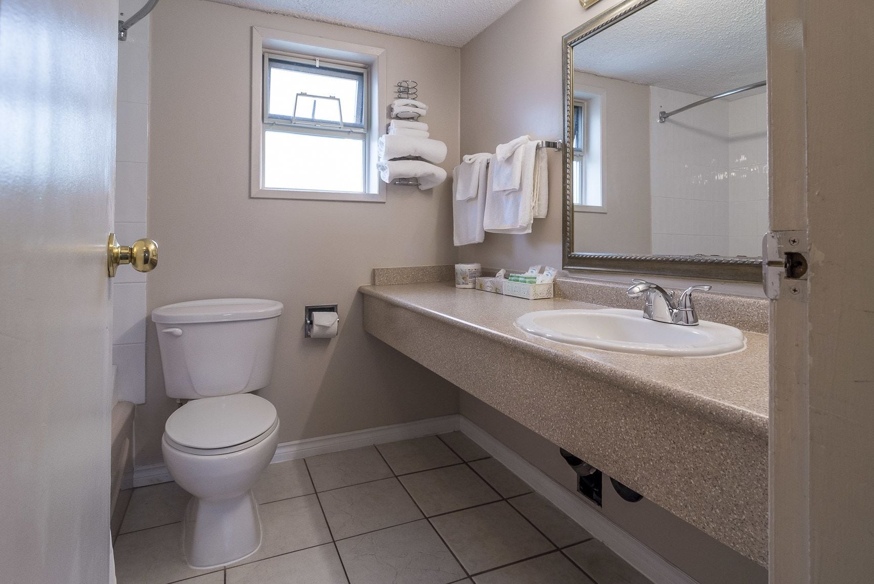 A bathroom with a toilet, sink, and a window.