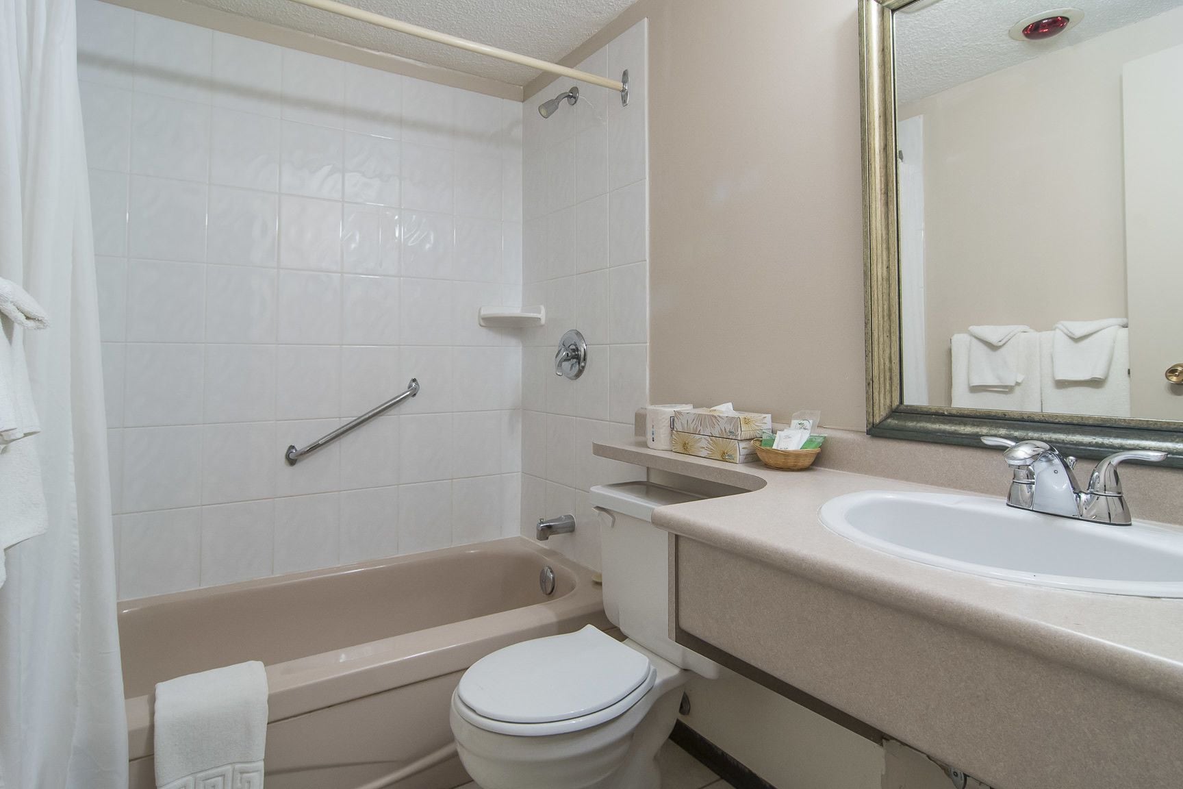 A bathroom with a bathtub, toilet, sink, and a mirror.
