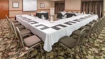 A conference room with a long table, chairs, and a projector screen.