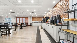 Un comedor amplio con una barra larga, diferentes opciones de asientos y una cocina con electrodomésticos y una estación de café.