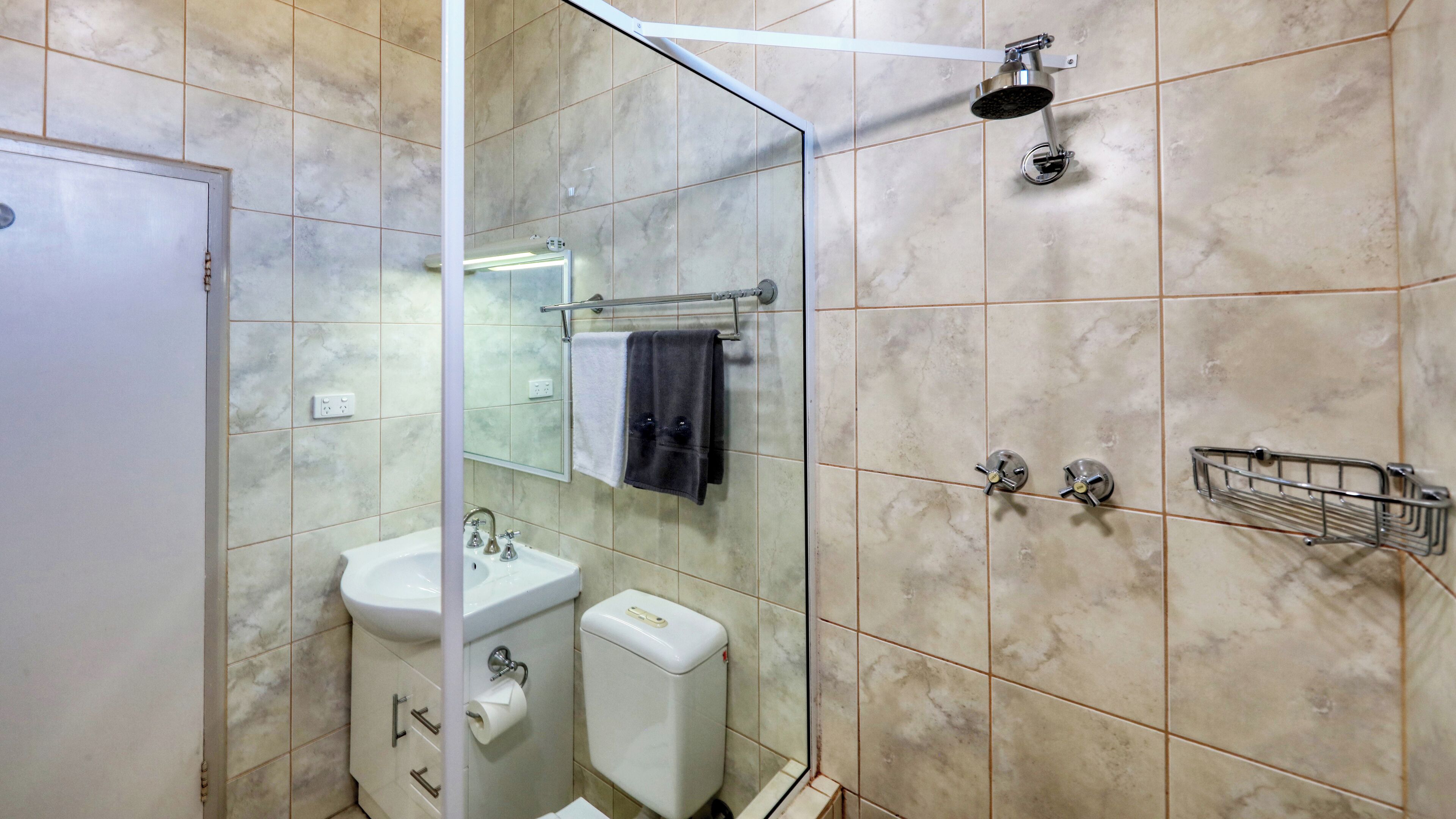 A bathroom with a glass shower enclosure, a sink, a toilet, and a towel rack.