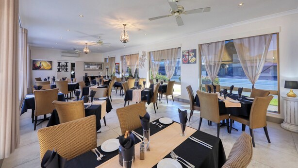 A spacious dining area with multiple tables and chairs, ceiling fans, and large windows offering views of the outside. - Silver Haven Motor Inn (Broken Hill)