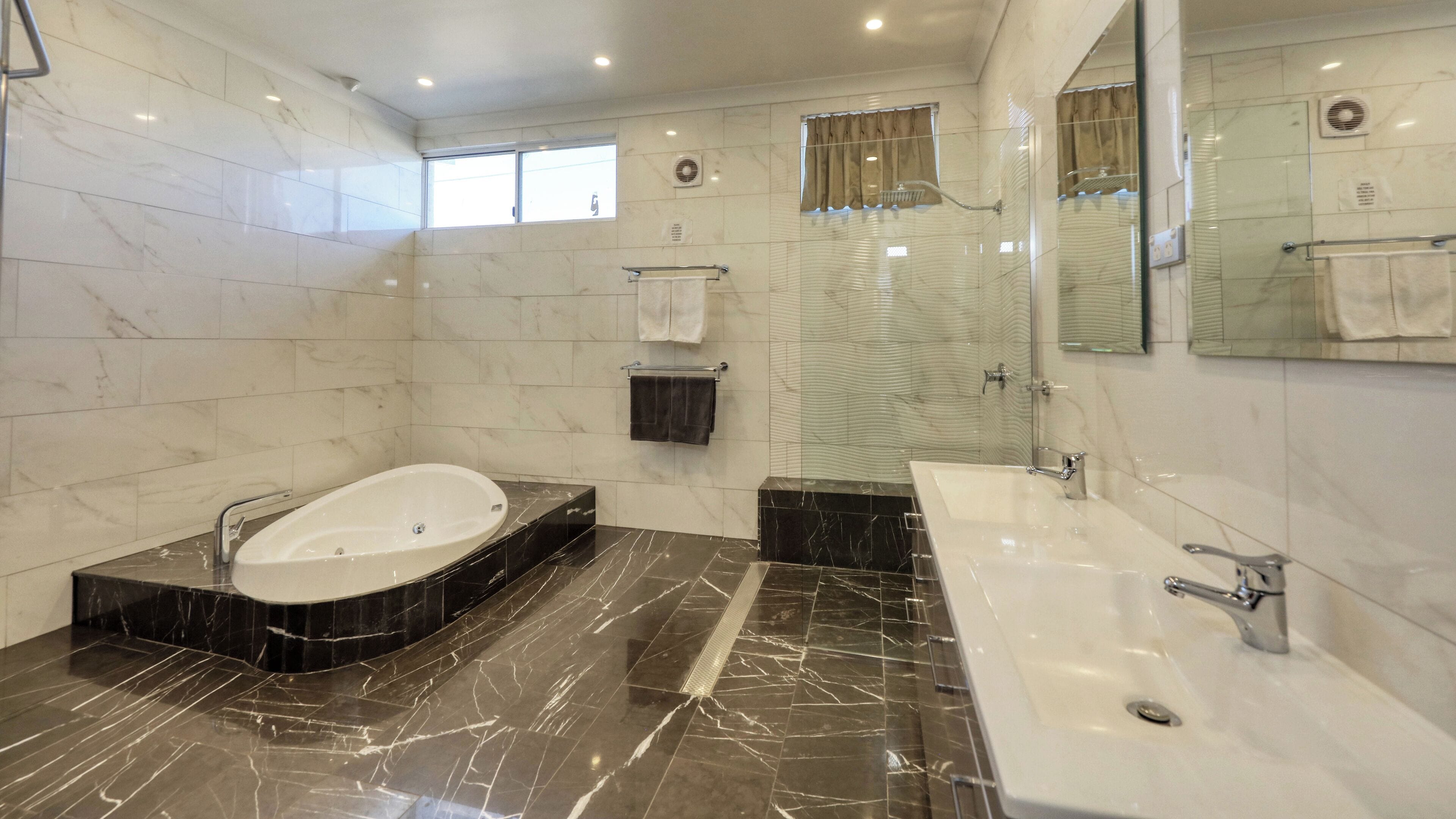 A modern bathroom with a large bathtub, a separate shower area, and a vanity with a sink.