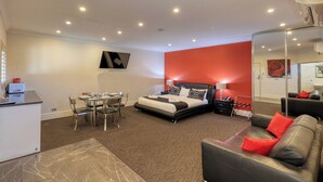 A modern hotel room with a bed, a dining table, and a seating area. - Silver Haven Motor Inn (Broken Hill)