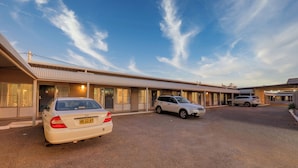 A motel with a row of rooms, a covered parking area, and a clear sky. - Silver Haven Motor Inn (Broken Hill)