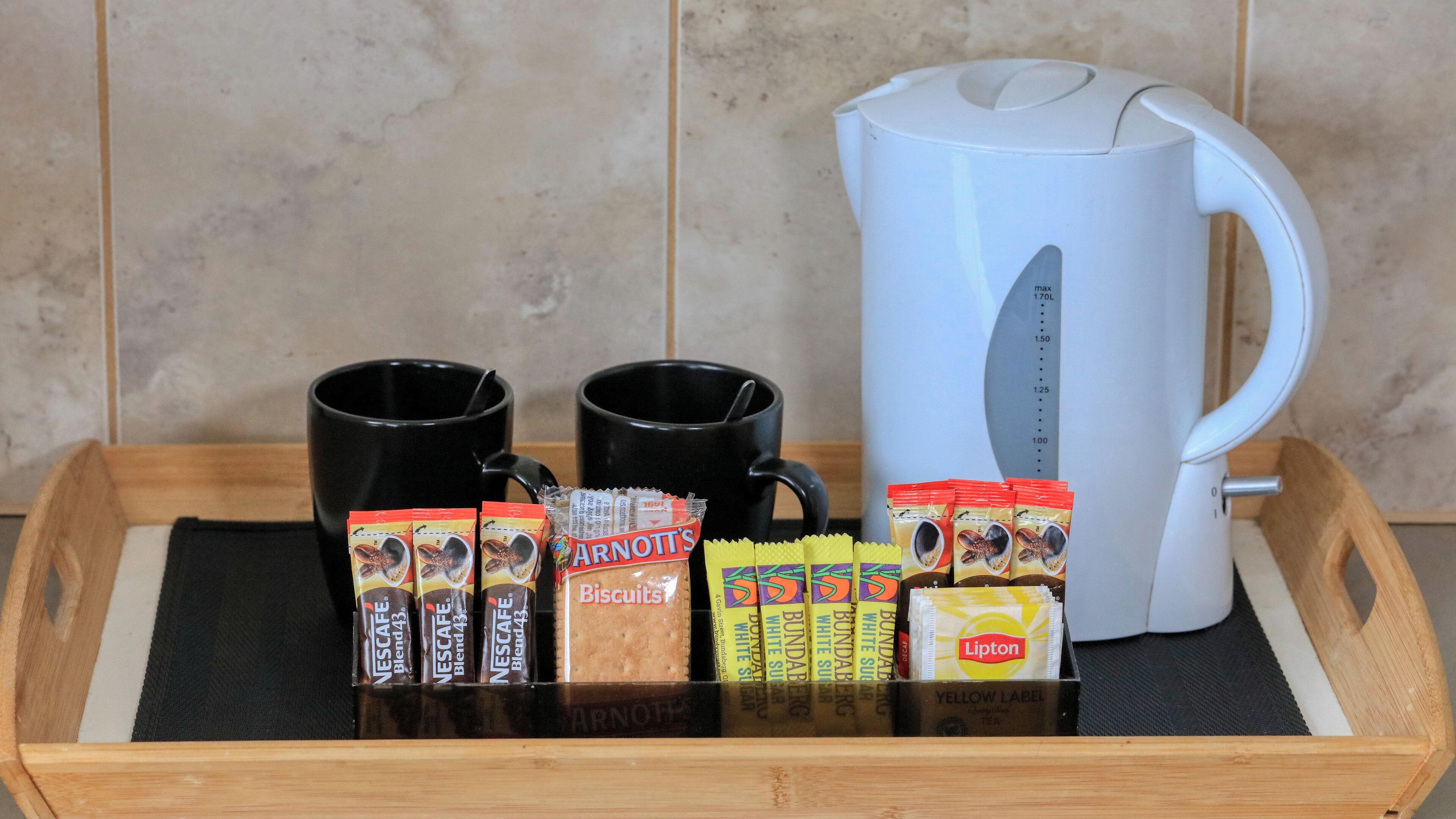 A tray with coffee packets, biscuits, and a white mug.
