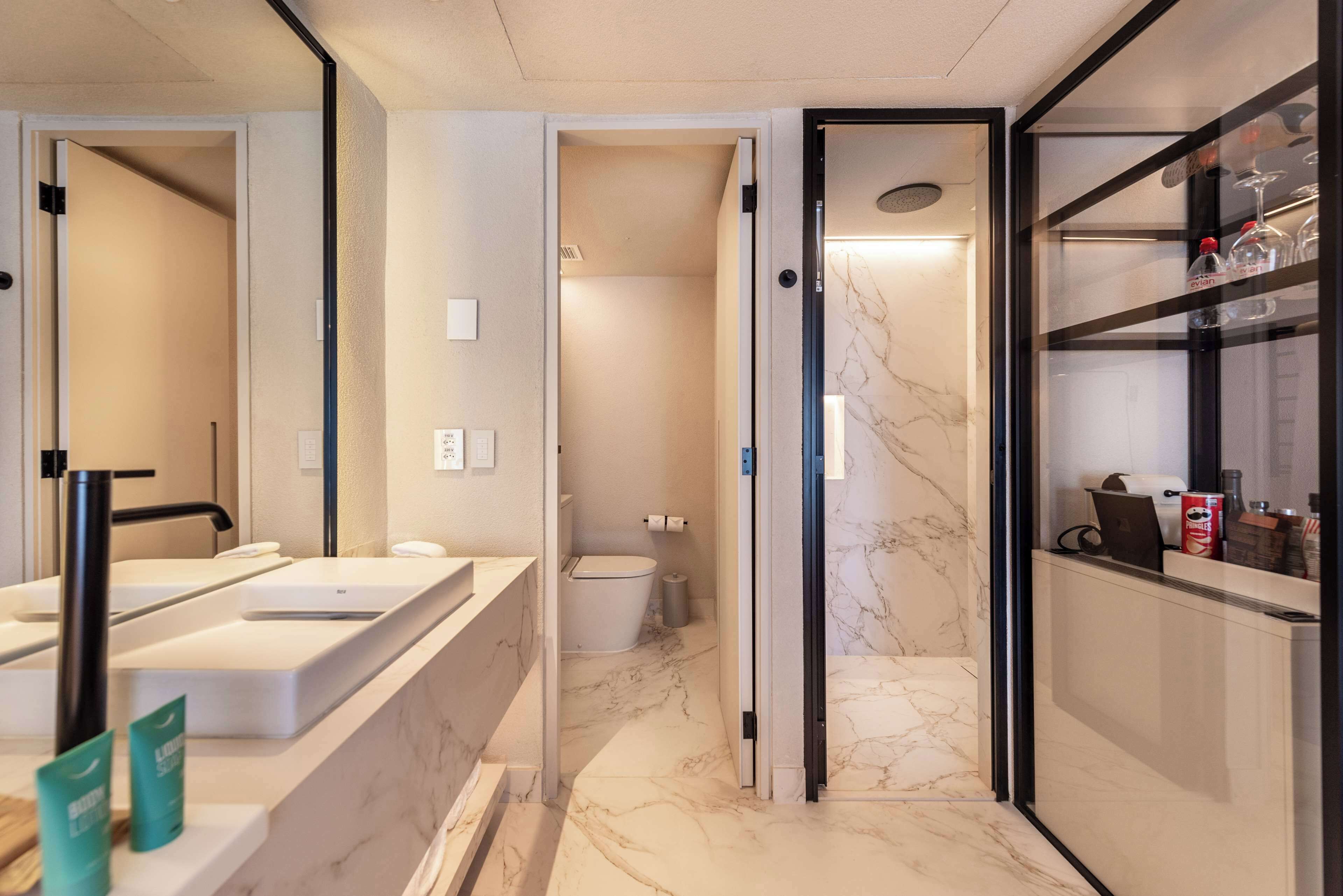 Une salle de bain moderne avec un sol en marbre, un grand miroir, un lavabo et des toilettes.