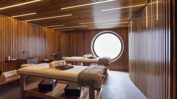 Une salle de spa moderne avec un lambris en bois, une table de massage, un lit de soins et une grande fenêtre circulaire.